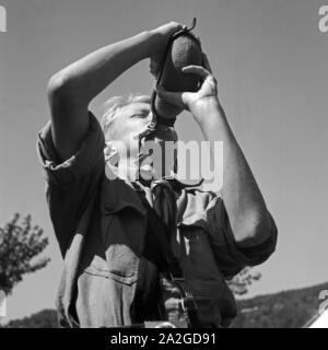 Durstiger Hitlerjunge trinkt aus thunfischwadenfänger Feldflasche im Hitlerjugend Lagerbier, Österreich 1930er Jahre. Durstig Hitle Jugend dirnking aus seiner Wasserflasche an die Hitler Jugend Camp, Österreich 1930. Stockfoto