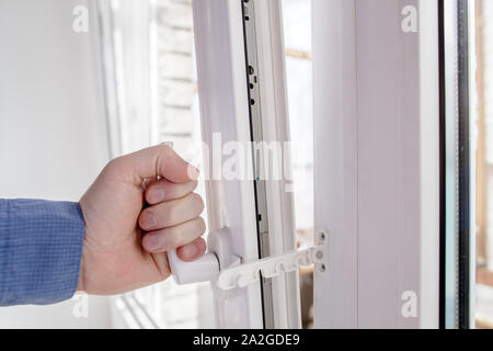 Die Hand hält das Handle des geöffneten Fenster mit sicheren Drossel Sperre verhindert das versehentliche Herunterfahren Stockfoto
