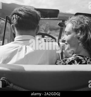 Eine Frau und ein Mann fahren in einem Opel Olympia, Deutschland 1930er Jahre. Eine Frau und ein Mann, der in s Opel Modell Olympia, Deutschland 1930. Stockfoto