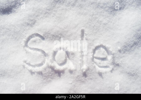 Wort VERKAUF horizontal in den Schnee an einem sonnigen Frühlingstag geschrieben. Stockfoto