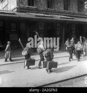 Skiurlauber vor dem Bahnhof in Landeck in Tirol, Deutschland 1930er Jahre. Ski Touristen am Bahnhof Landeck, Deutschland 1930. Stockfoto