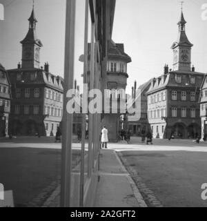 Eine Kleinstadt spiegelt sich im-Schaufenster eines Geschäfts, Deutschland 1930er Jahre. Eine kleine Stadt im Schaufenster auf einer Einkaufsstraße widerspiegelt, Deutschland 1930. Stockfoto