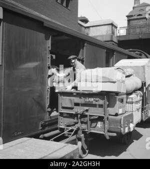 Gepäckträger mit dem zugangsweg am Bahnhof in Hamburg, Deutschland 1930er Jahre. Gepäckträger auf einer Plattform des Hamburger Hauptbahnhofs, Deutschland 1930. Stockfoto