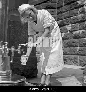 Eine Krankenschwester Im Kurbad Bad Homburg eine Einer Heilwasserquelle, 1930er Jahre Deutschland. Eine Krankenschwester auf einen Brunnen Heilwasser bei Kurort Bad Homburg, Deutschland der 1930er Jahre. Stockfoto