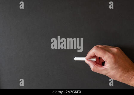 Zurück zu Schule - eine leere Tafel und eines Lehrers Hand einen Stock von Chalk stellt einen Neuanfang für junge Köpfe. Stockfoto