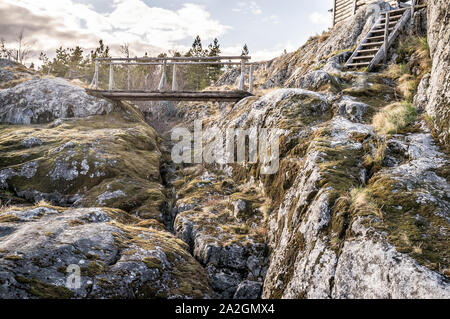 Holzbrücke und Treppen zu der alten Hütte auf einer felsigen Insel im Hintergrund des Waldes. Stockfoto