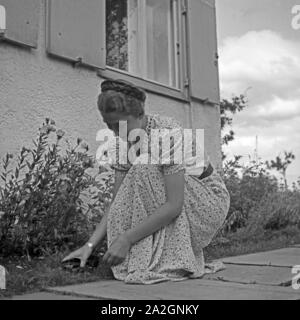 Eine junge Frau beim Unkrautjäten im Vorgarten, Deutschland 1930er Jahre. Eine junge Frau, die in ihrem Garten Jäten, Deutschland 1930. Stockfoto