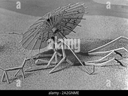Papiermännchen-Szenerie: Streichholzmännchen Pärchen unter einem Sonnenschirm am Strand, Deutschland 1930er Jahre. Finger puppet Szenarien: Passt auf Leute unter einem Sonnenschirm am Strand, Deutschland 1930. Stockfoto