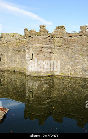 Eine der seitlichen Türme mit Reflexion in den Wassergraben in Beaumaris Castle auf Anglesey im Norden von Wales. Stockfoto