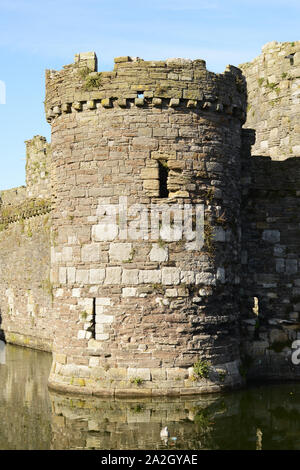 Eine der seitlichen Türme mit Reflexion in den Wassergraben in Beaumaris Castle auf Anglesey im Norden von Wales. Stockfoto