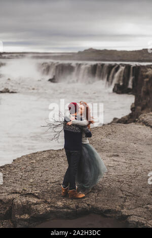 Happy hipster verliebtes Paar in Island. Traditionelle wolle Pullover, rote Haare, Grauer Rock. Berühmten Wasserfall Selfoss auf Hintergrund, dramatische nordischen Landschaft. Stockfoto