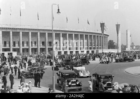 Eine Menschenmenge einer Straße mit Taxis vor dem Stadion in Berlin, Deutschland, 1930er Jahre. Masse an einer stark befahrenen Straße mit Taxis vor dem Olympiastadion Berlin, Deutschland 1930. Stockfoto