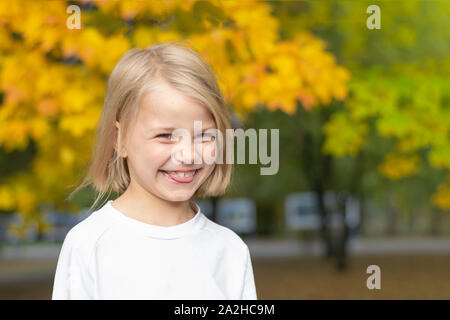 Porträt einer wenig schönen Mädchen auf einem Hintergrund von bunten Herbst Bäume im Park. Übersicht Zunge Stockfoto