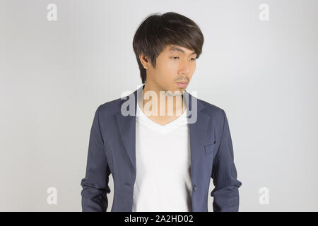 Portrait asiatischen Casual Geschäftsmann in blauen Anzug mit T-Shirt unten auf grauem Hintergrund. Casual Geschäftsmann tragen Anzug Mode in semi-formale St Stockfoto