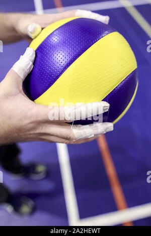 Der Athlet hält den Ball für Volleyball in seinen Händen umklammerte ihn mit bandagierten Finger. Close-up. Stockfoto