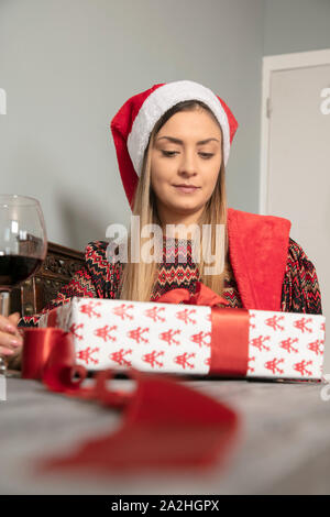 Junge schöne Mädchen wraps Geschenke für Weihnachten, das Trinken von Wein Stockfoto