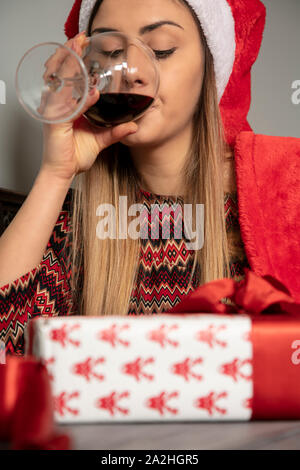 Junge schöne Mädchen wraps Geschenke für Weihnachten, das Trinken von Wein Stockfoto