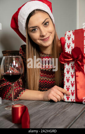 Junge schöne Mädchen wraps Geschenke für Weihnachten, das Trinken von Wein Stockfoto