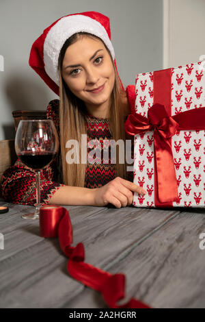 Junge schöne Mädchen wraps Geschenke für Weihnachten, das Trinken von Wein Stockfoto