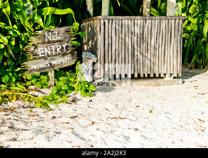 Holzschild am Rande des Strands, das Ihnen sagt, dass es sich um ein Privateigentum handelt, kein Eingang mit Pfosten, Holzhütte. Stockfoto