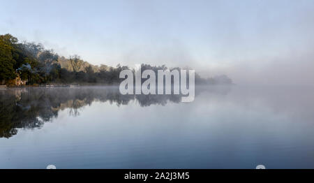 Reflexionen im Herbst Nebel am frühen Morgen auf Esthwaite Water in der Nähe von Ambleside Stockfoto