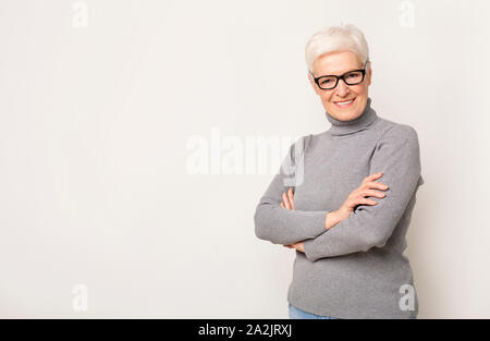 Zuversichtlich ältere Frau in Gläsern Stehen mit verschränkten Armen Stockfoto