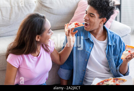 Schöne afrikanische amerikanische Paar teilen Pizza am Tag zu Hause. Stockfoto