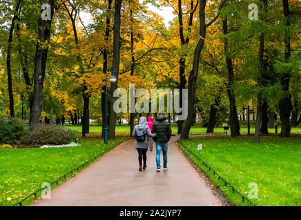 St. Petersburg, Russland, 3. Oktober 2019. Herbst Farben an einem regnerischen Tag mit Bäume im Herbst in Mikhaylovskiy Garten. Ein paar wenige auf dem Fußweg Stockfoto