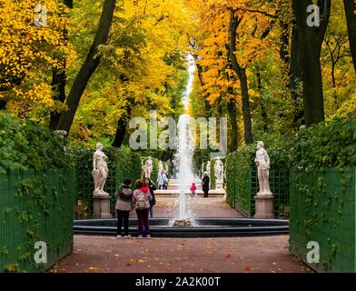 St. Petersburg, Russland, 3. Oktober 2019. Herbst Farben beleben einen trüben regnerischen Tag für Touristen. Herbst Bäume im Sommer Garten mit einem Brunnen Stockfoto