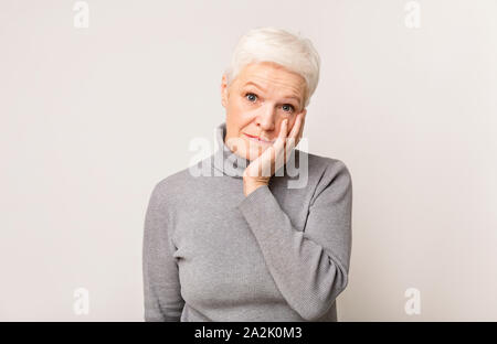 Senior woman holding Wange bis insgesamt Unglauben schockiert Stockfoto