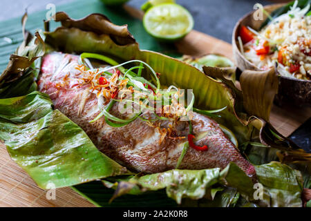 Red Snapper im Bananenblatt und Papaya Salat Stockfoto