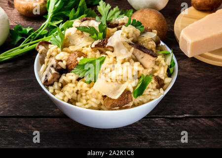 Risotto ai Funghi, Pilze Reis mit Zutaten auf einem dunklen Holzmöbeln im Landhausstil Hintergrund Stockfoto