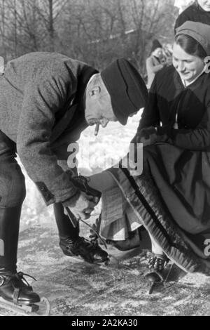 Mein Mann hilft einer Frau beim Anschnallen von Schlittschuhkufen im Spreewald, Deutschland, 1930er Jahre. Ein Mann, eine Frau auf schlittschuh Läufer im Spreewald, Deutschland 1930. Stockfoto