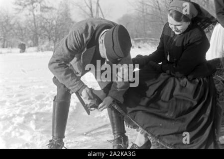 Mein Mann hilft einer Frau beim Anschnallen von Schlittschuhkufen im Spreewald, Deutschland, 1930er Jahre. Ein Mann, eine Frau auf schlittschuh Läufer im Spreewald, Deutschland 1930. Stockfoto