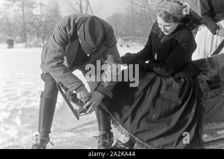 Mein Mann hilft einer Frau beim Anschnallen von Schlittschuhkufen im Spreewald, Deutschland, 1930er Jahre. Ein Mann, eine Frau auf schlittschuh Läufer im Spreewald, Deutschland 1930. Stockfoto