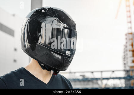Close up Portrait von Biker in geschlossenen schwarz glänzenden Helm auf städtischen Hintergrund. Stockfoto