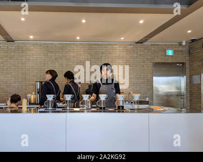 SEPT. 19, 2019 - Seoul, Südkorea: Schöne asiatische Frau mit grauen Schürze und schwarzen Uniformen Kaffee für Kunden bei einem Kaffee sho zu dienen Stockfoto