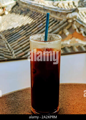 Soda mit Eiswürfeln in ein Glas und eine blaue staw. Stockfoto