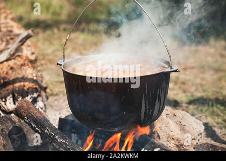 Kochen eine Suppe mit Gemüse in einem Kessel über offenem Feuer, Camping Essen Stockfoto