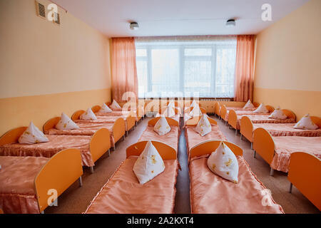 Zustell- und Kinderbetten sind in einem hellen Schlafsaal von einem Baumschule. eine Menge von Kinderbetten. Stockfoto