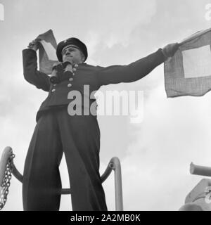 Original-Bildunterschrift: Dienst des Matrosen: Signalwinken ein Bord eines Torpedoboots, Deutschland 1940er Jahre. Flagge Semaphore auf Deck eines Torpedoboot, Deutschland 1940. Stockfoto