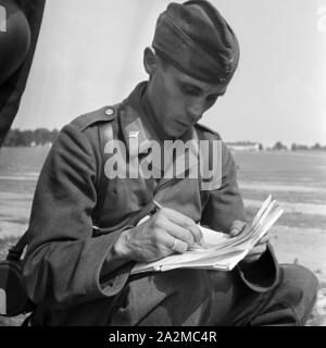 Original-Bildunterschrift: Soldat der Nachrichtentruppe bei der Aufnahme einer Meldung / Diktat Waden abhörenden Kameraden, Deutschland 1940er Jahre. Soldat des Signal Corps Aufnahme eines diktiert Hinweis von seinem Kameraden, Deutschland 1940. Stockfoto