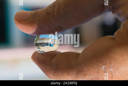 Reflexion in einem Haus in einer Hydro gel Ball. Ein Haus in ein Hydro Ball mit grünem Hintergrund verschwommen. Stockfoto