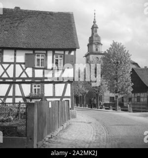 Blick in ein idylllisches Dorf mit Fachwerkhaus und Kirchturm, Deutschland 1930er Jahre. Blick auf ein idyllisches Dorf mit Fachwerkhaus und Kirche, Deutschland 1930. Stockfoto