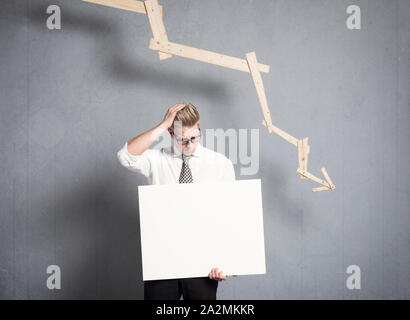 Frustriert Geschäftsmann holding Verkleidung vor Grafik unten zeigt. Stockfoto