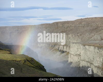 Ein Regenbogen Formen in der Gischt der Wasserfälle Dettifoss in Island mächtige Ströme von Wasser in die Schlucht unten. Stockfoto