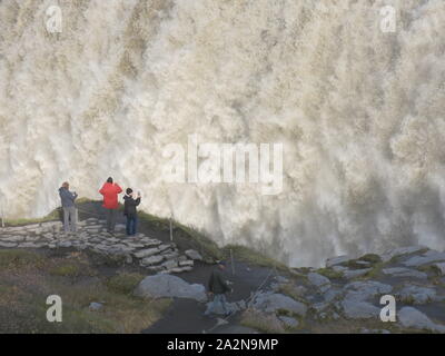 Touristen Foto Dettifoss, der größte Wasserfall in Island das Entladen einer leistungsstarken torrent von Wasser in der Schlucht unten. Stockfoto