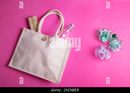 Wiederverwendbare eco Baumwolltasche mit einem Glas Flasche und drei zerknittert Plastikflaschen auf einem hellen Rosa fuchsia Hintergrund. Null Abfall Konzept Stockfoto