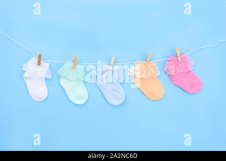 Bunt süß Baby Socken hängen auf der Wäscheleine auf blauem Hintergrund. Baby Accessoires. Flach. Stockfoto