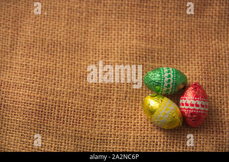 Einen dekorativen Hintergrund für Ostern mit bunten Eiern auf einem braunen Sack und Platz für Texte oder Grafiken hinzu. Platz kopieren Stockfoto
